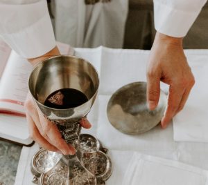 person holds chalice with liquid on table