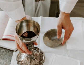 person holds chalice with liquid on table